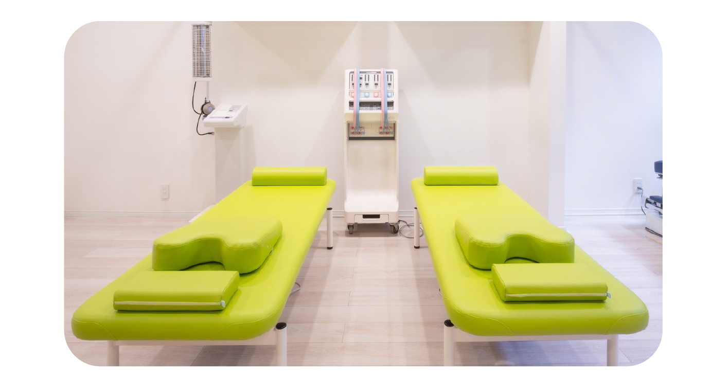 光が差し込む施術スペースに整然と配置された緑の施術ベッド。