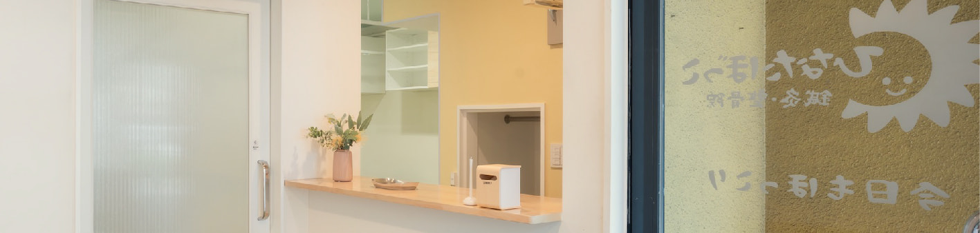 明るい陽射しが差し込む待合スペース。落ち着いた雰囲気のソファと観葉植物。